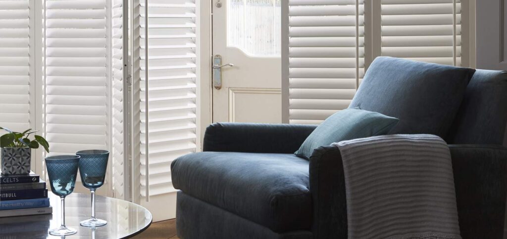 dark blue armchair against a series of full height shutters in Stowmarket