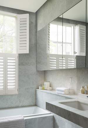 Bathroom decorated in grey with a large mirror and tier on tier shutters in Suffolk